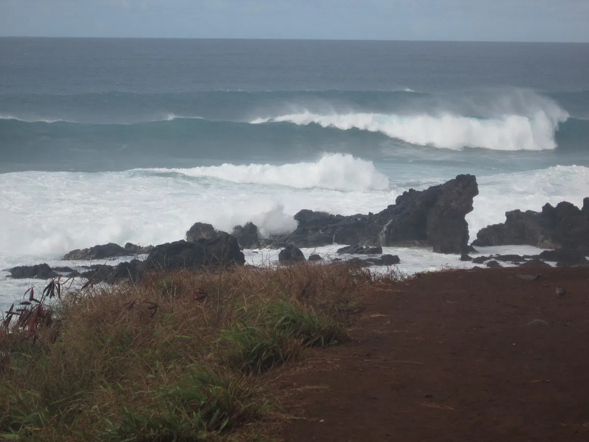 Waves breaking on black lava rock along the Pāʻia shoreline on Maui