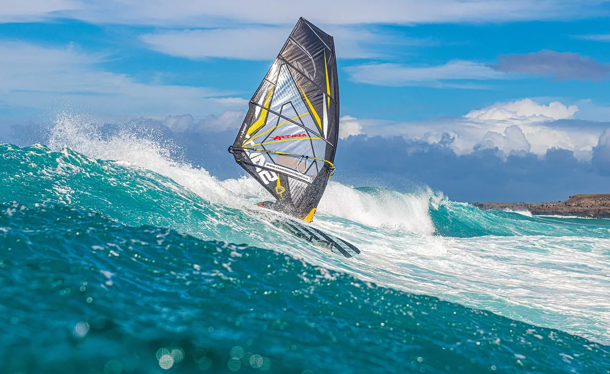 A windsurfer launching off a breaking wave at Hoʻokipa Beach on Maui's North Shore